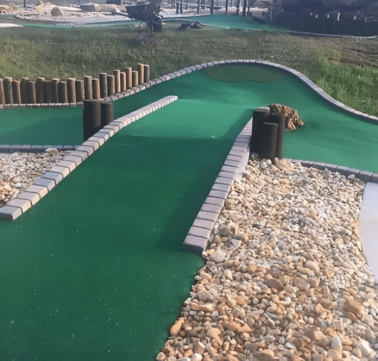 A mini golf course with green and white rocks.